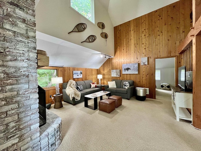 carpeted living room with high vaulted ceiling and wooden walls