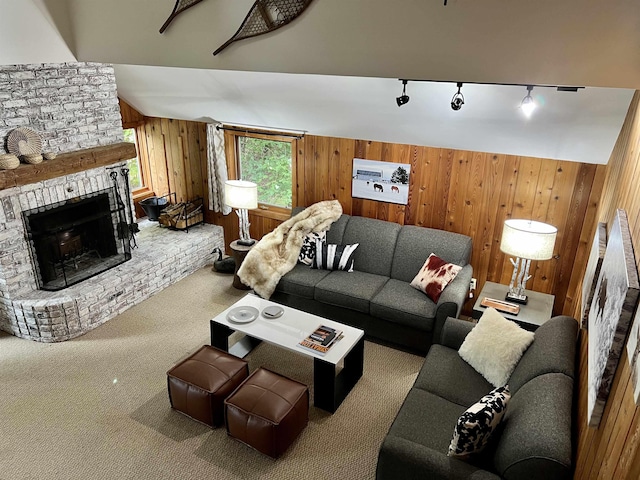 carpeted living room with rail lighting, vaulted ceiling, a brick fireplace, and wood walls