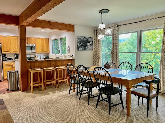 carpeted dining room featuring beamed ceiling