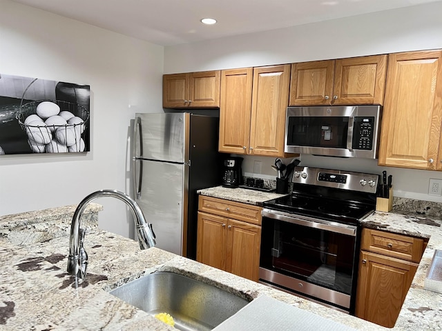 kitchen with light stone countertops, appliances with stainless steel finishes, and sink