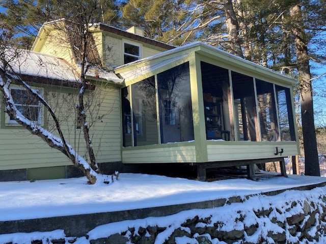 snow covered property featuring a sunroom