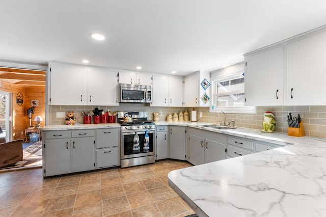 kitchen featuring backsplash, stainless steel appliances, sink, and white cabinets