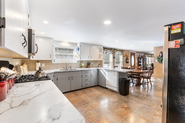 kitchen with stainless steel appliances, kitchen peninsula, sink, and backsplash