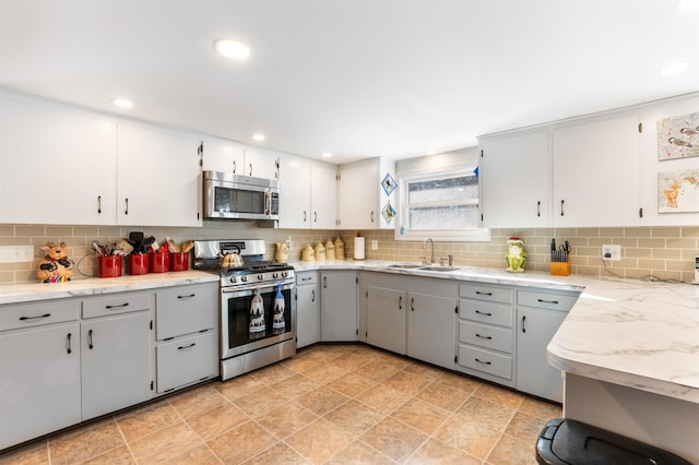 kitchen with sink, gray cabinetry, appliances with stainless steel finishes, white cabinets, and backsplash