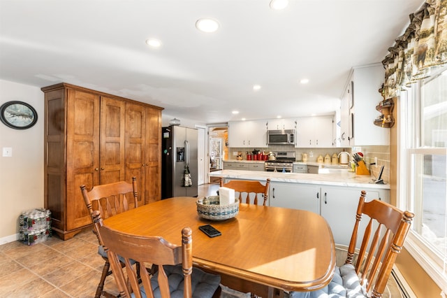 dining room featuring a baseboard radiator, plenty of natural light, sink, and light tile patterned floors