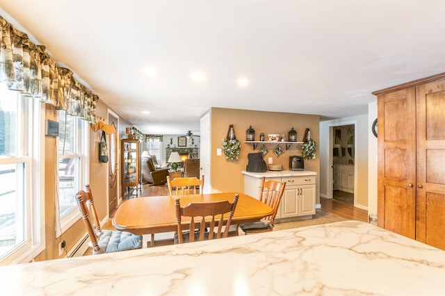 dining space with ceiling fan, light wood-type flooring, and a fireplace