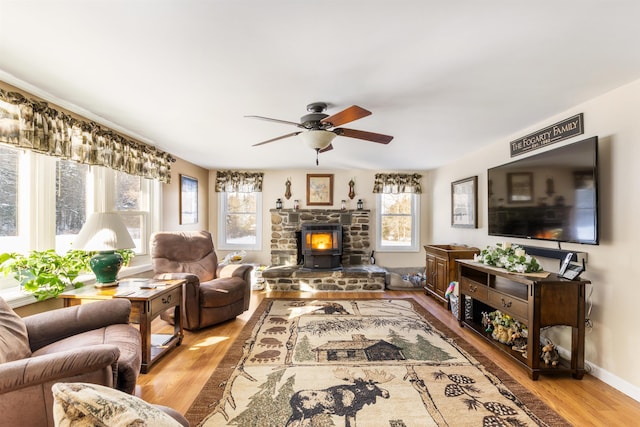 living room featuring a wood stove, ceiling fan, and light hardwood / wood-style flooring