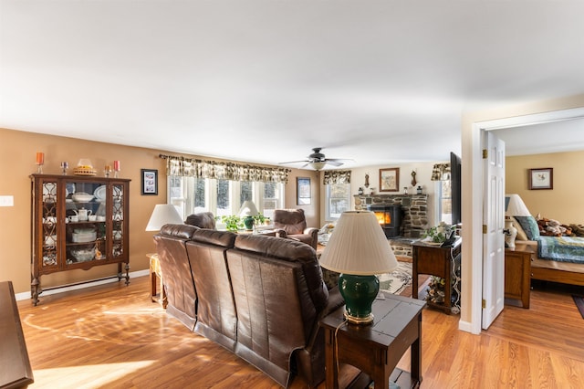 living room with ceiling fan, a fireplace, and light hardwood / wood-style floors