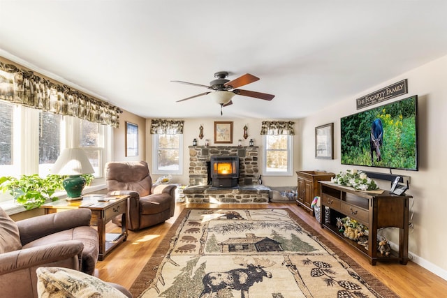 living room featuring ceiling fan, light hardwood / wood-style flooring, and a wood stove