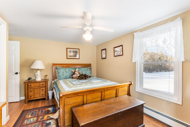 bedroom with ceiling fan, light wood-type flooring, and baseboard heating