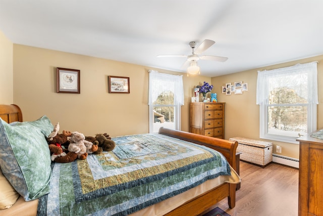 bedroom with a baseboard radiator, hardwood / wood-style floors, and ceiling fan