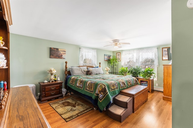 bedroom featuring light wood-type flooring, multiple windows, and a baseboard heating unit