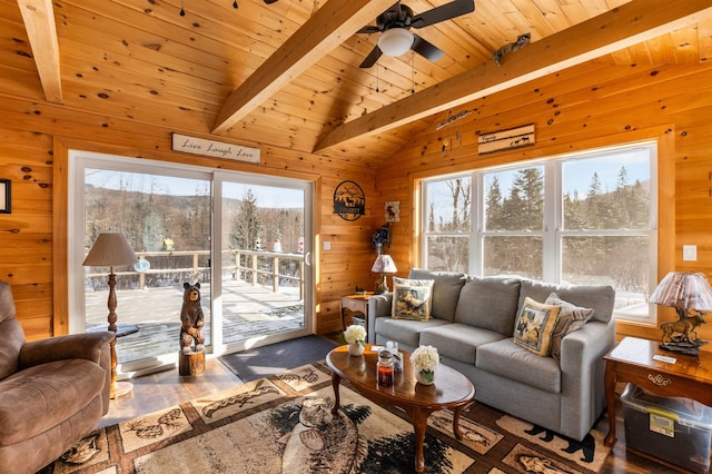 living room with a wealth of natural light, lofted ceiling with beams, and wood walls