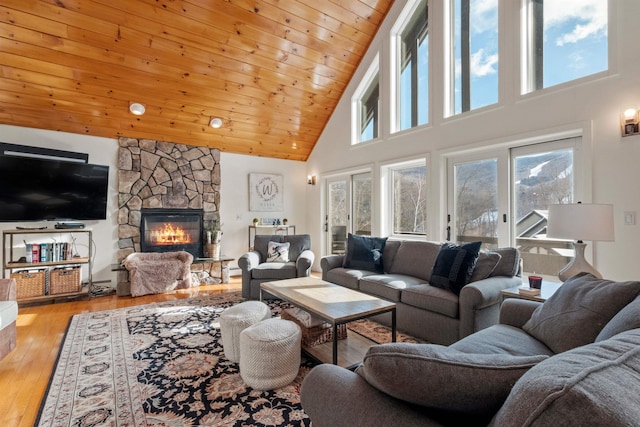 living room with wood ceiling, high vaulted ceiling, a fireplace, and light hardwood / wood-style floors