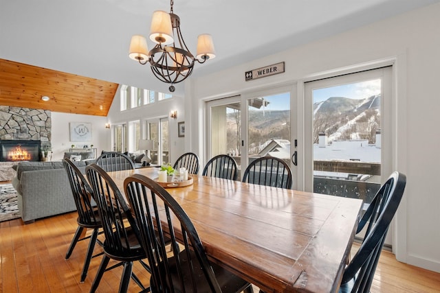 dining area featuring lofted ceiling, plenty of natural light, a fireplace, and a mountain view