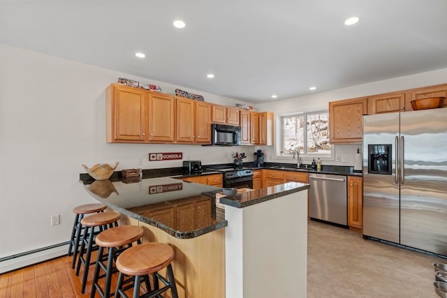 kitchen featuring sink, a breakfast bar area, kitchen peninsula, dark stone counters, and black appliances