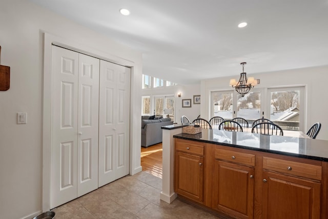 kitchen featuring dark stone countertops, light tile patterned floors, decorative light fixtures, and a chandelier