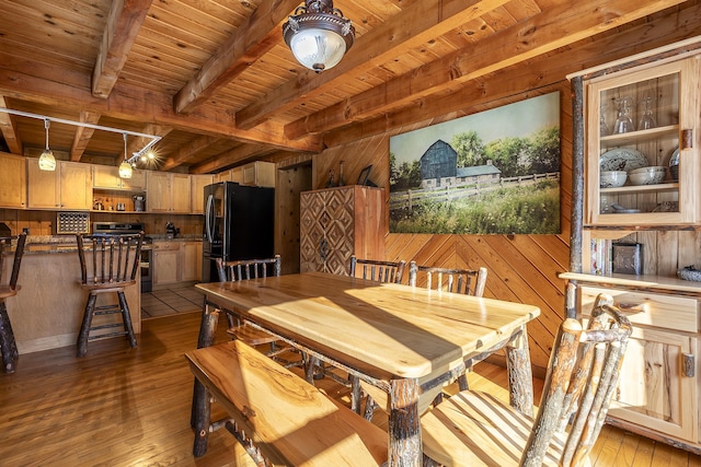 dining space featuring beamed ceiling, wood walls, wooden ceiling, and light hardwood / wood-style flooring