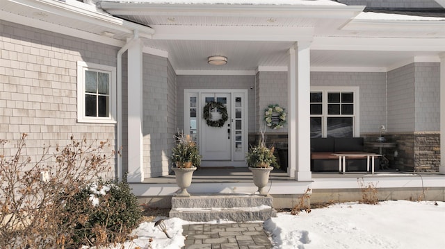 snow covered property entrance featuring a porch