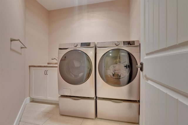 laundry room with cabinets, washer and clothes dryer, and light tile patterned floors