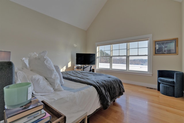 bedroom featuring high vaulted ceiling and light wood-type flooring