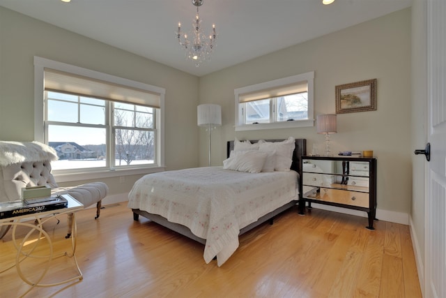 bedroom featuring multiple windows, a notable chandelier, and light hardwood / wood-style floors