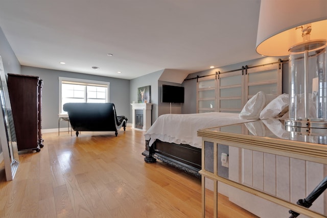 bedroom featuring a barn door and light wood-type flooring