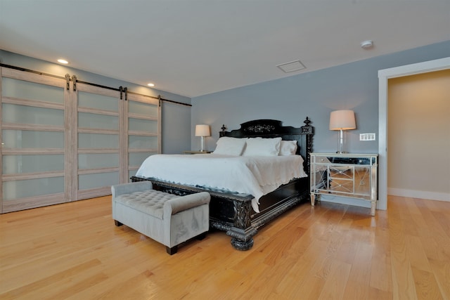 bedroom featuring a barn door and light hardwood / wood-style flooring