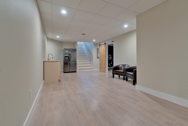 interior space featuring a barn door, sink, a paneled ceiling, and light hardwood / wood-style floors