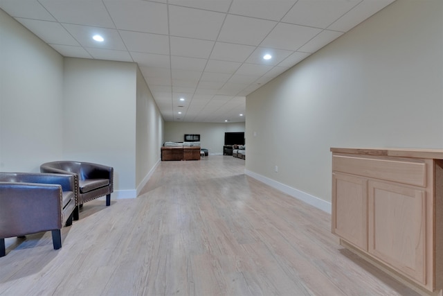 living area with a drop ceiling and light hardwood / wood-style floors