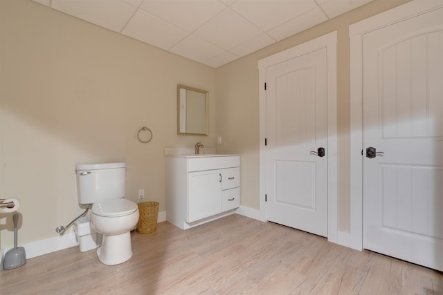 bathroom with a paneled ceiling, vanity, toilet, and hardwood / wood-style floors