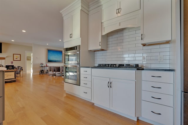 kitchen featuring white cabinetry, appliances with stainless steel finishes, backsplash, and light hardwood / wood-style flooring