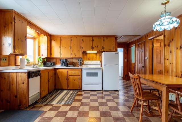 kitchen featuring wood walls, white appliances, and decorative light fixtures