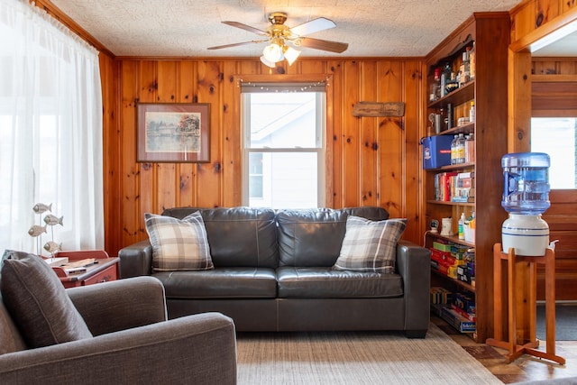 living room featuring a textured ceiling, ceiling fan, and wood walls