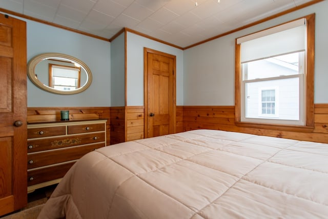 bedroom with ornamental molding, a closet, and wood walls