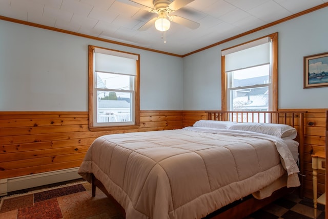 bedroom with multiple windows, wooden walls, ornamental molding, and a baseboard radiator