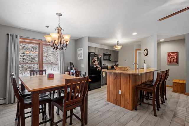 dining room with ceiling fan with notable chandelier and light hardwood / wood-style floors