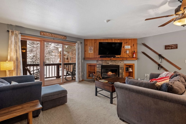 living room with ceiling fan, light colored carpet, a textured ceiling, and a fireplace