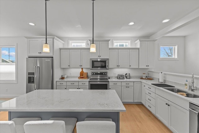 kitchen with stainless steel appliances, a breakfast bar, sink, and hanging light fixtures