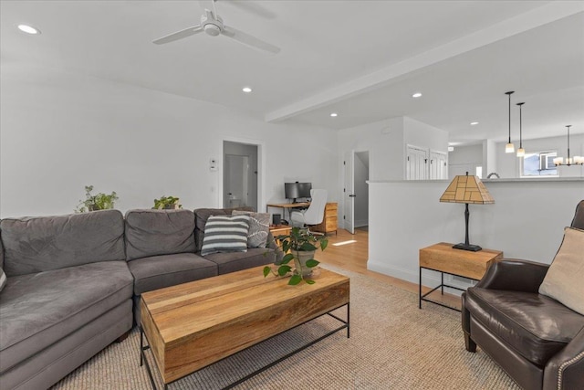 living room featuring ceiling fan with notable chandelier, light hardwood / wood-style floors, and beamed ceiling