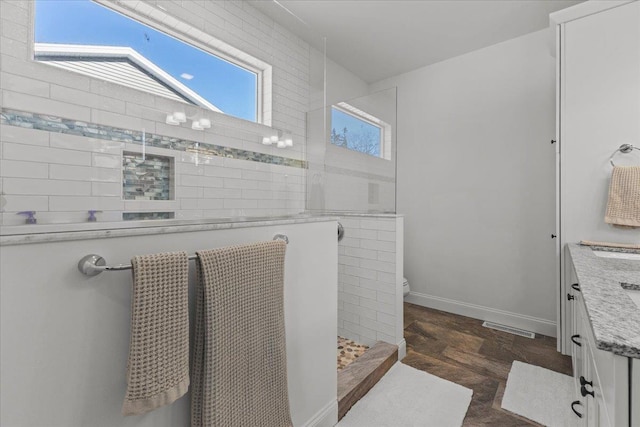 bathroom featuring vanity, toilet, and tiled shower