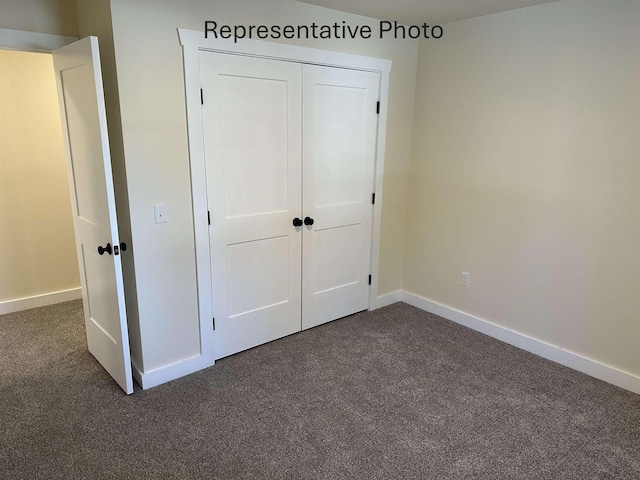 unfurnished bedroom featuring dark carpet and a closet