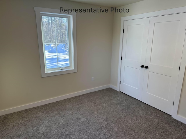 unfurnished bedroom featuring a closet, dark carpet, and multiple windows