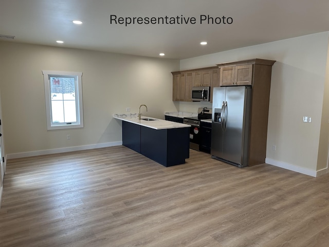 kitchen featuring stainless steel appliances, sink, kitchen peninsula, and light hardwood / wood-style floors