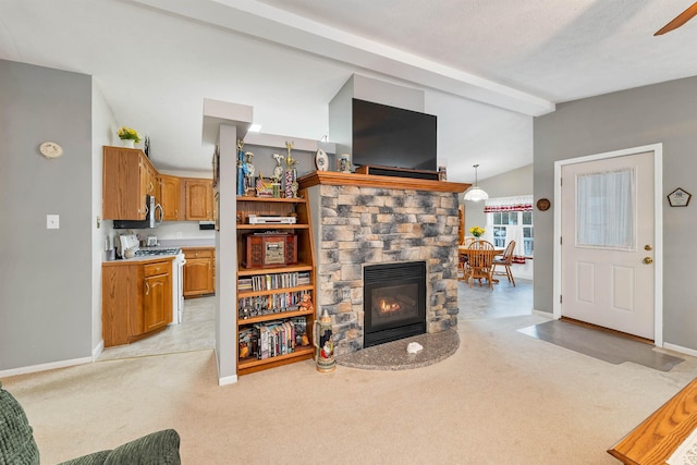 living room featuring a stone fireplace, lofted ceiling with beams, and light colored carpet