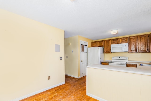 kitchen featuring white appliances, sink, and light hardwood / wood-style floors