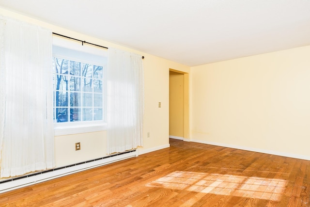 unfurnished room featuring a baseboard heating unit and hardwood / wood-style floors