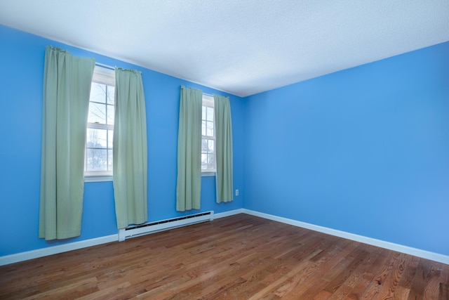 unfurnished room with a baseboard heating unit and dark wood-type flooring