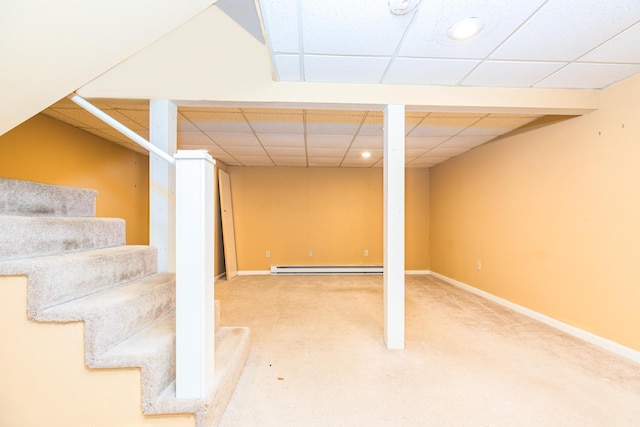 basement featuring a paneled ceiling, carpet, and baseboard heating