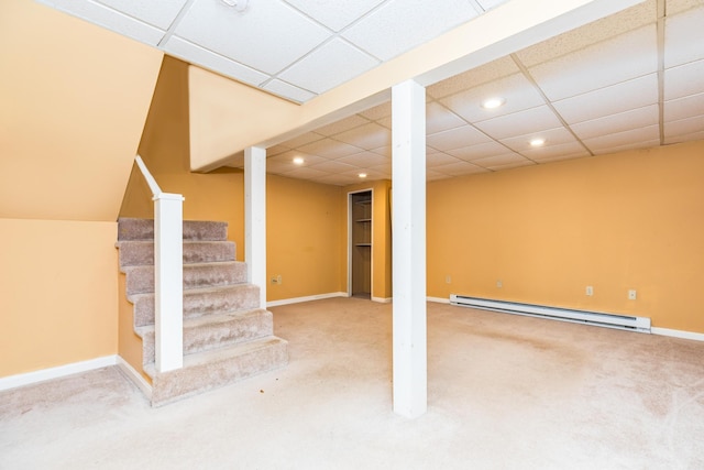 basement featuring a baseboard radiator, a paneled ceiling, and carpet floors